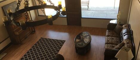 A spacious living room with a large window, a sofa, a coffee table, and a decorative chandelier.