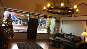 A living room with a chandelier, a Christmas tree, a sofa, and a coffee table. - Hotel Burgess (Reedley)