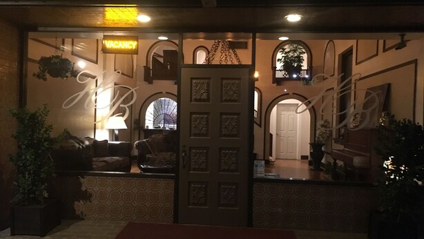 A hotel lobby with a reception desk, a 'VACANCY' sign, a 'No Smoking' sign, and a 'WiFi' sign. - Hotel Burgess (Reedley)