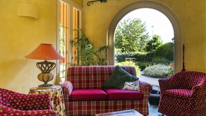 Una sala de estar acogedora con un sofá rojo, sillones estampados y una mesa de centro de madera.