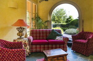 Uma sala de estar acolhedora com um sofá vermelho, poltronas estampadas e uma mesa de centro de madeira.