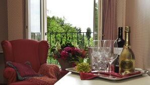 Una habitación con un sillón rojo, una mesa con una botella de champán, copas y una bandeja con flores.
