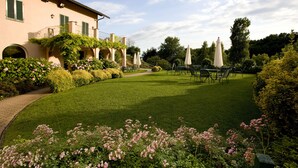 Un jardín bien cuidado con un sendero pavimentado, setos podados y una zona de estar exterior con sombrillas.