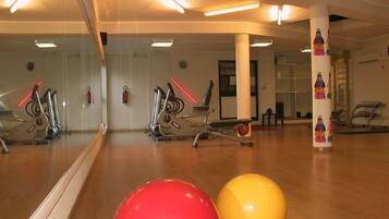 A gym with exercise equipment, a large mirror, and exercise balls.