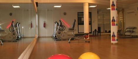 Uma academia com equipamentos de exercícios, um espelho grande e bolas de ginástica.