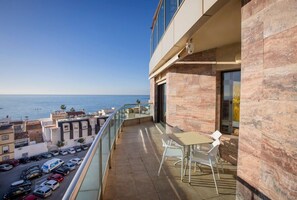 A balcony with a view of the sea, a table and chairs, and parked cars below. - Bluesea Calabahía (Rincon de la Victoria)
