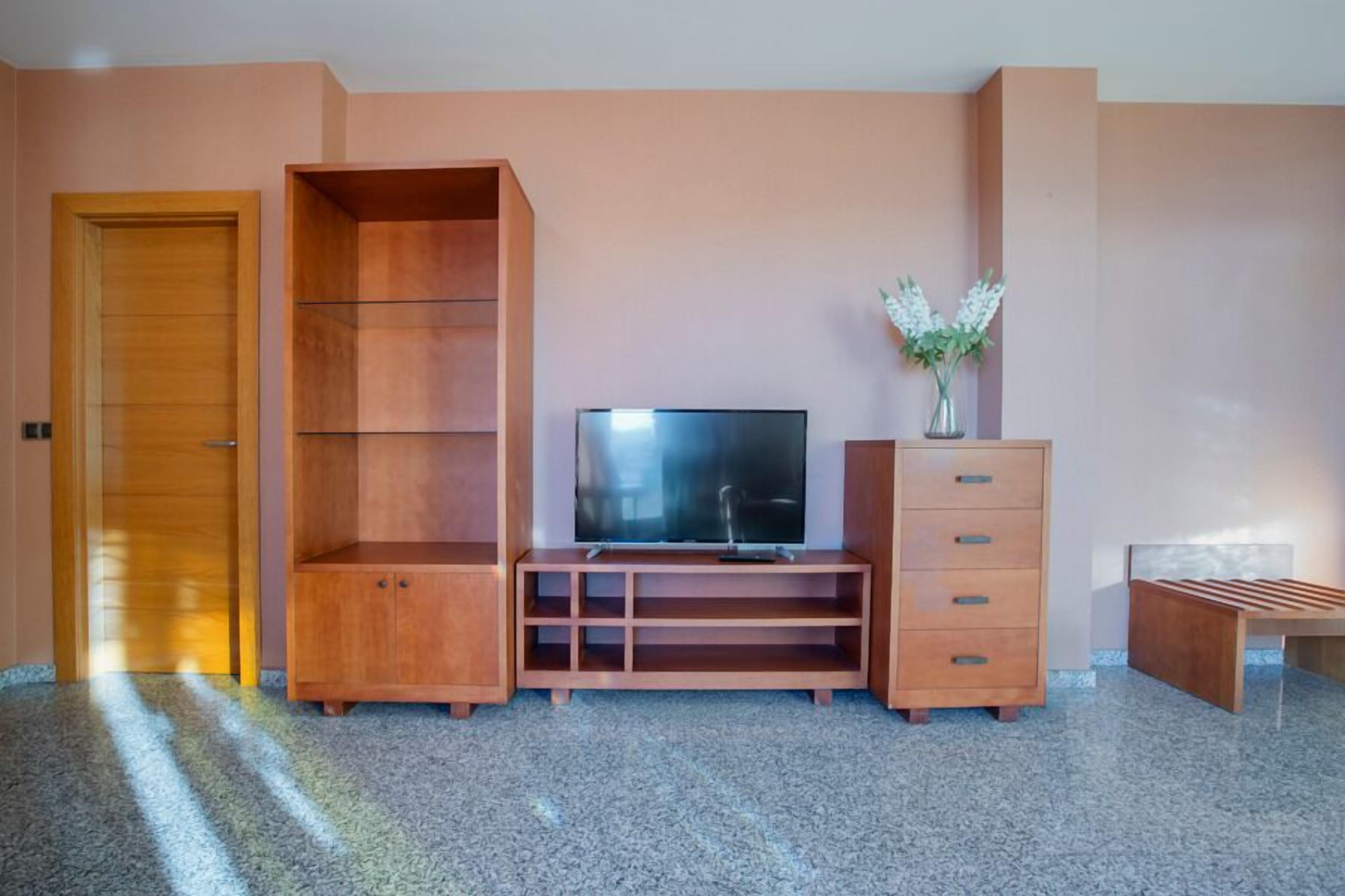 Une pièce comprenant un meuble de rangement en bois, un téléviseur à écran plat et un petit meuble avec des tiroirs.