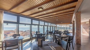 Un restaurante con vistas al mar, techo de madera y mobiliario moderno.