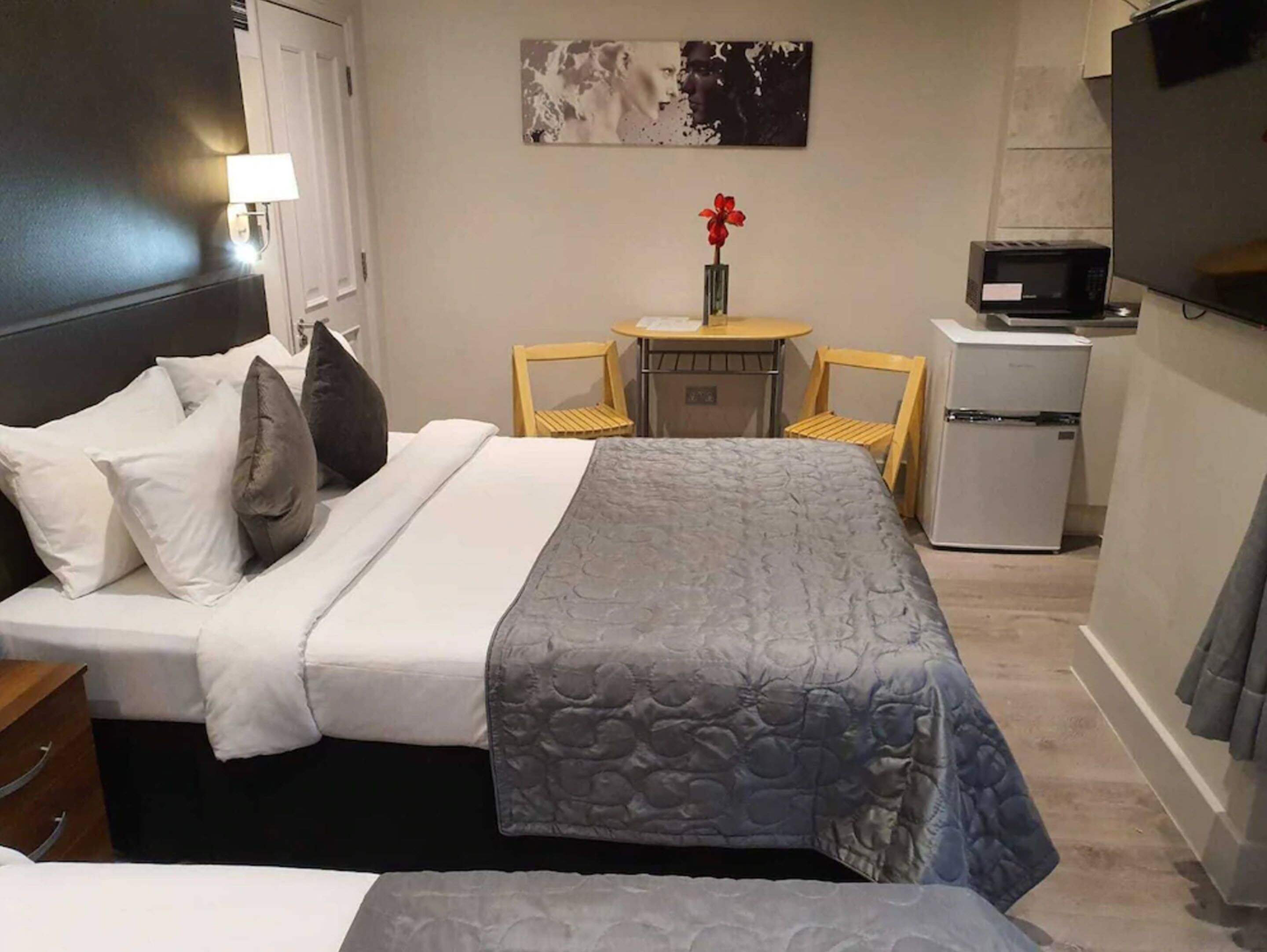 Ein Hotelzimmer mit Bett, einem kleinen Tisch mit Stuhl, einer Mikrowelle und einem Kühlschrank.