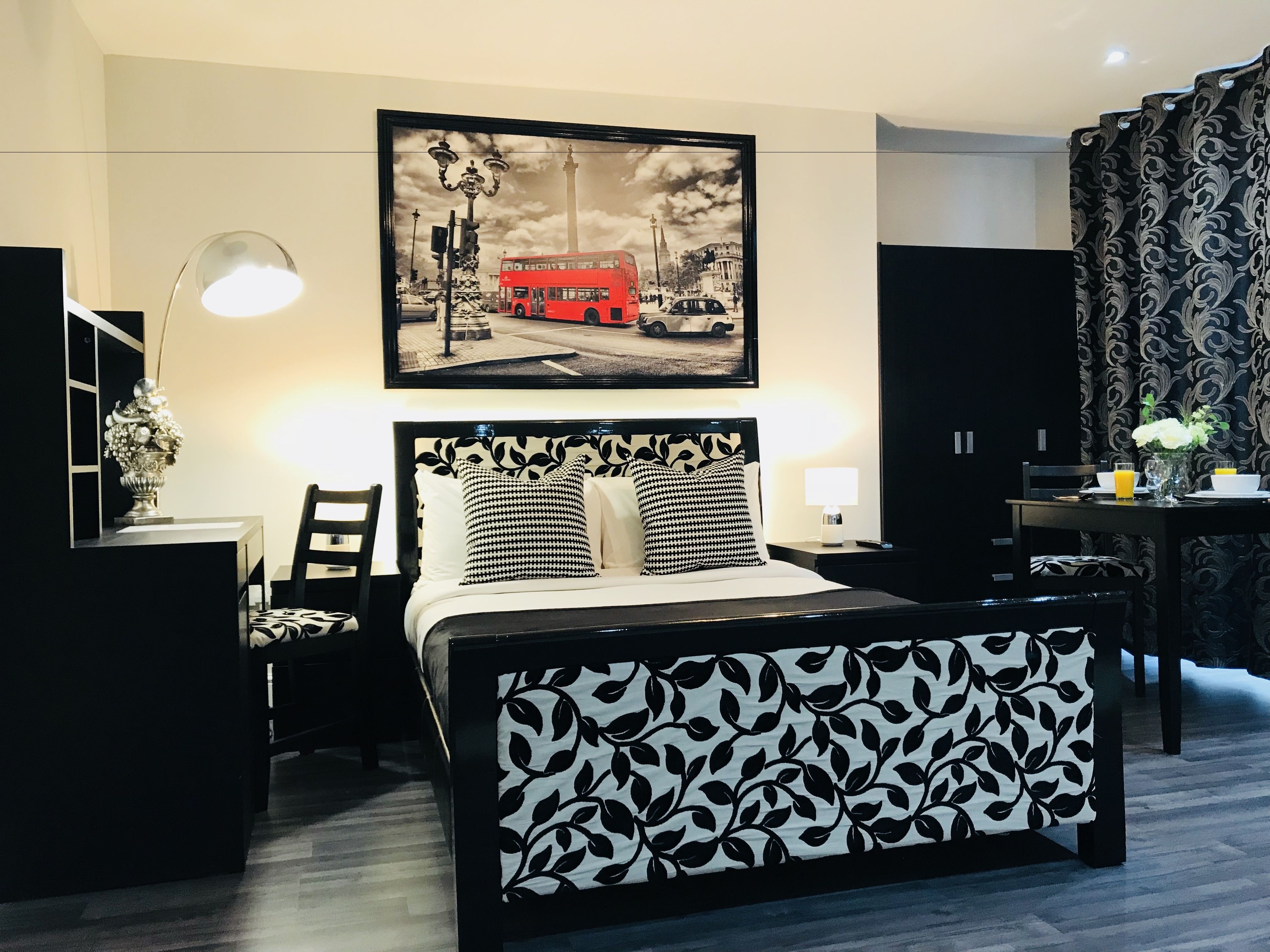 A modern hotel room with a bed, bedside tables, a desk, and a chair.