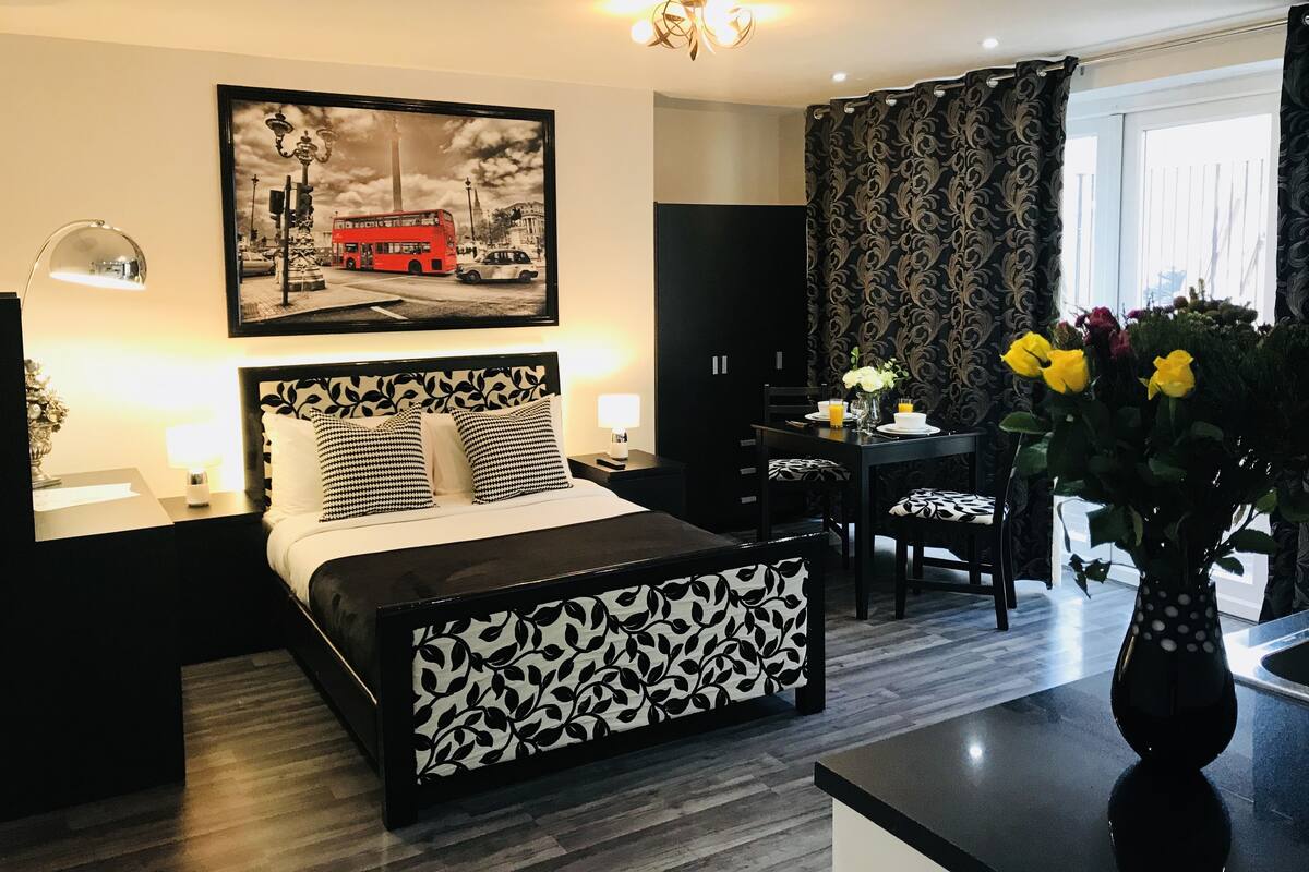 A modern hotel room with a large bed, a desk, and a dining area.