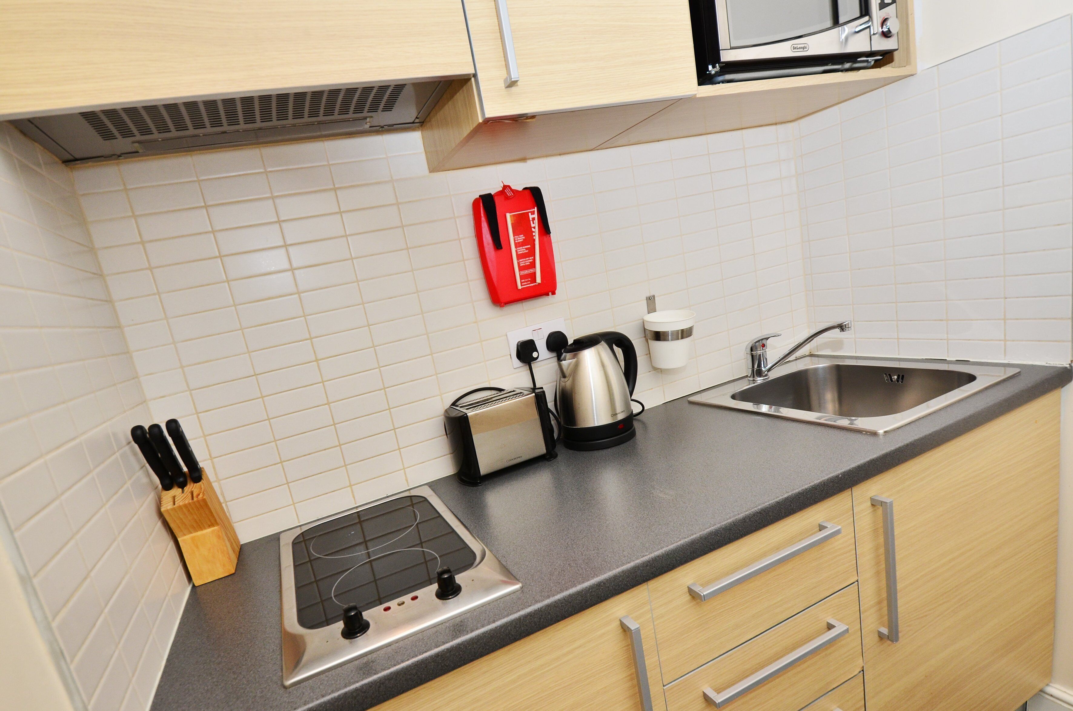 Een keuken met een magnetron, broodrooster, waterkoker, spoelbak en een messenblok.
