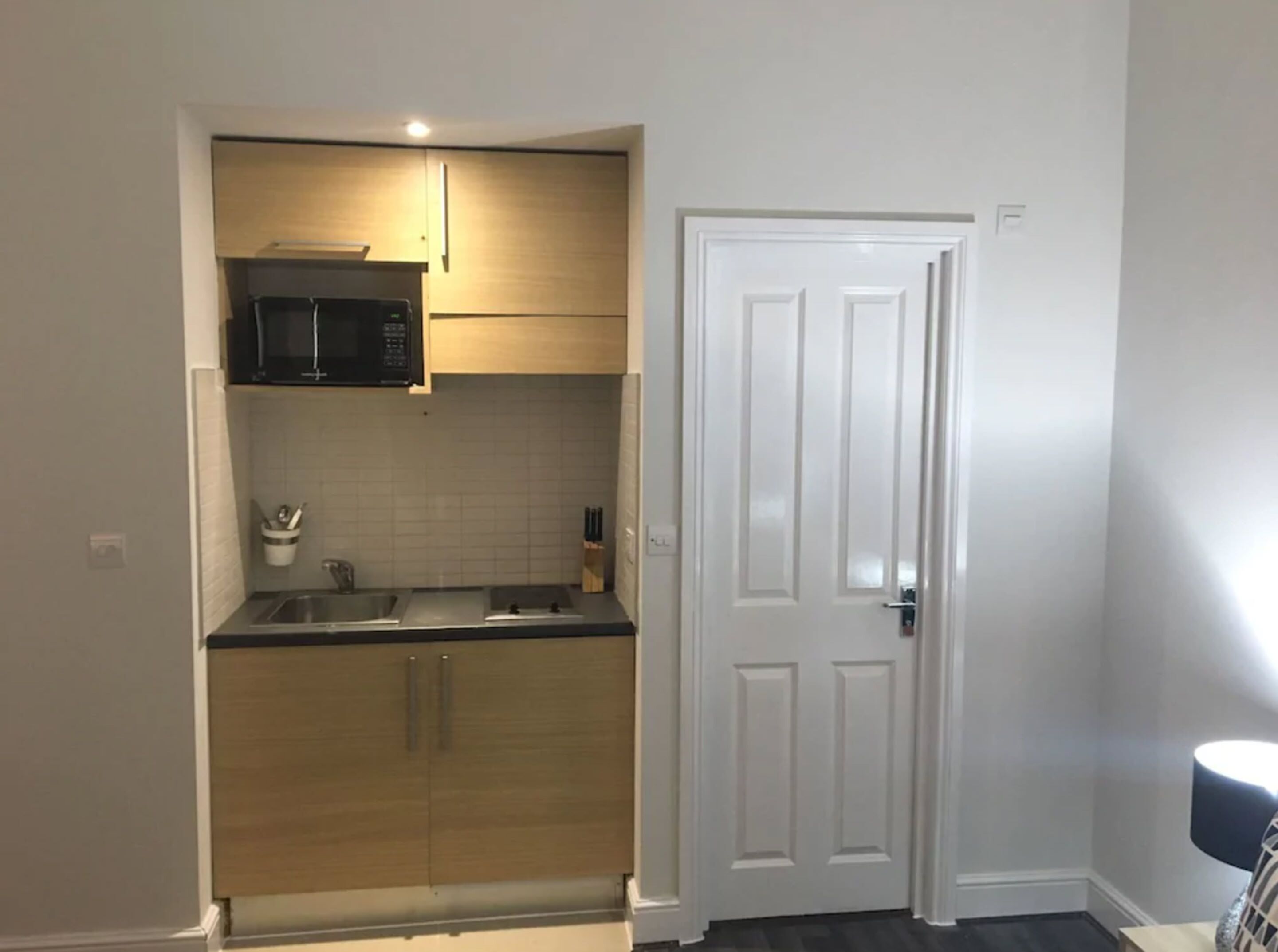 A compact kitchen with wooden cabinets, a microwave, and a sink.