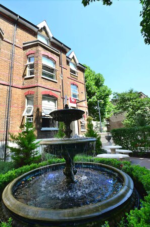 A brick building with a fountain in the foreground. - W6 Hotel Hammersmith (London)