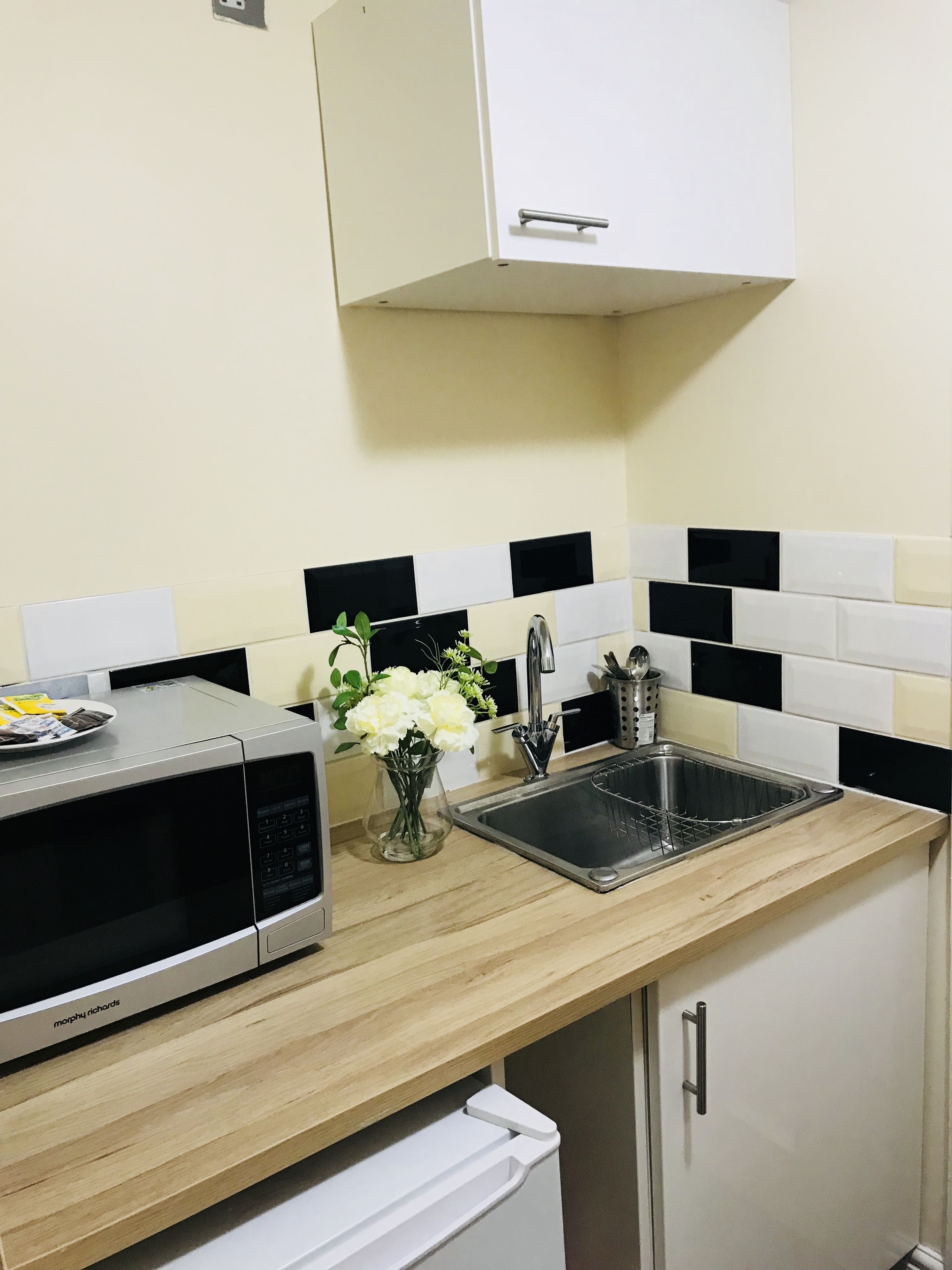 A kitchen with a microwave, sink, and cabinet.