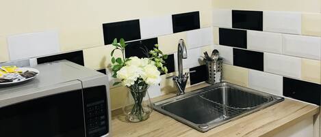 A kitchen with a microwave, sink, and cabinet.