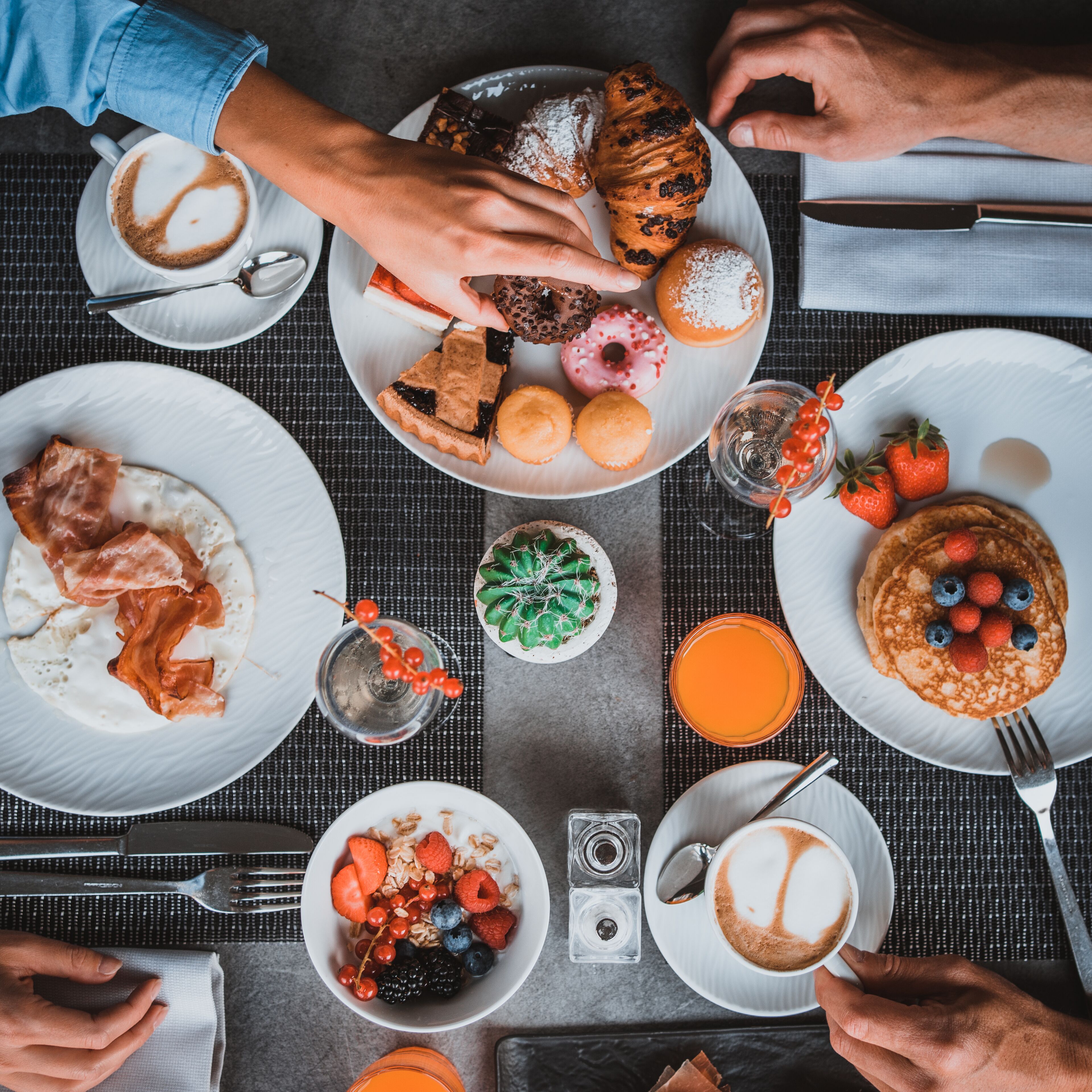 A breakfast setting with various dishes including pastries, fruits, and beverages on a table.