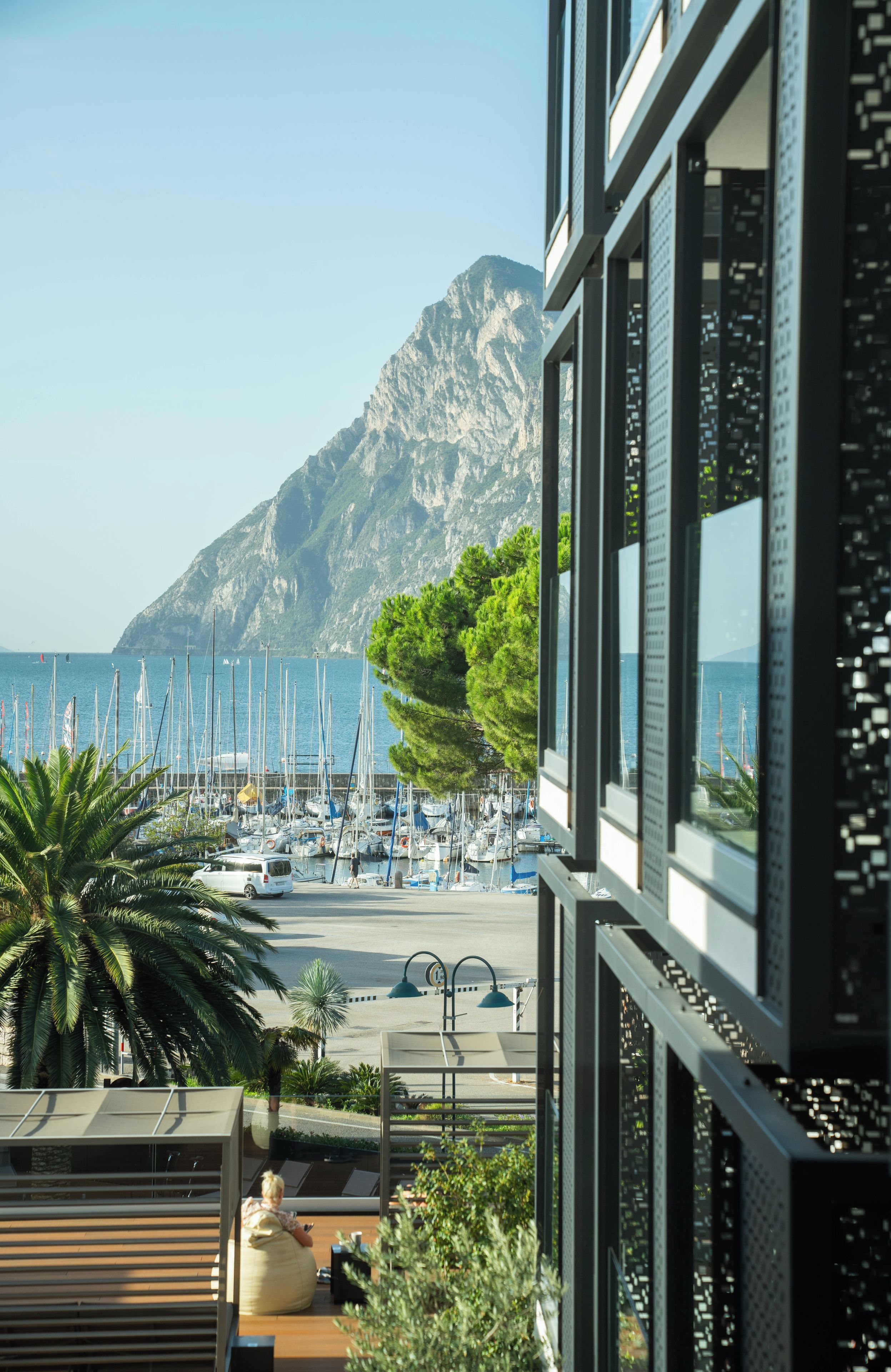 A marina with boats, a mountain in the background, and a modern building with large windows.