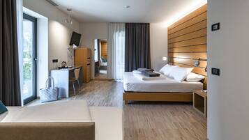 A modern hotel room with a bed, bedside table, desk, chair, and a view of the outdoors.