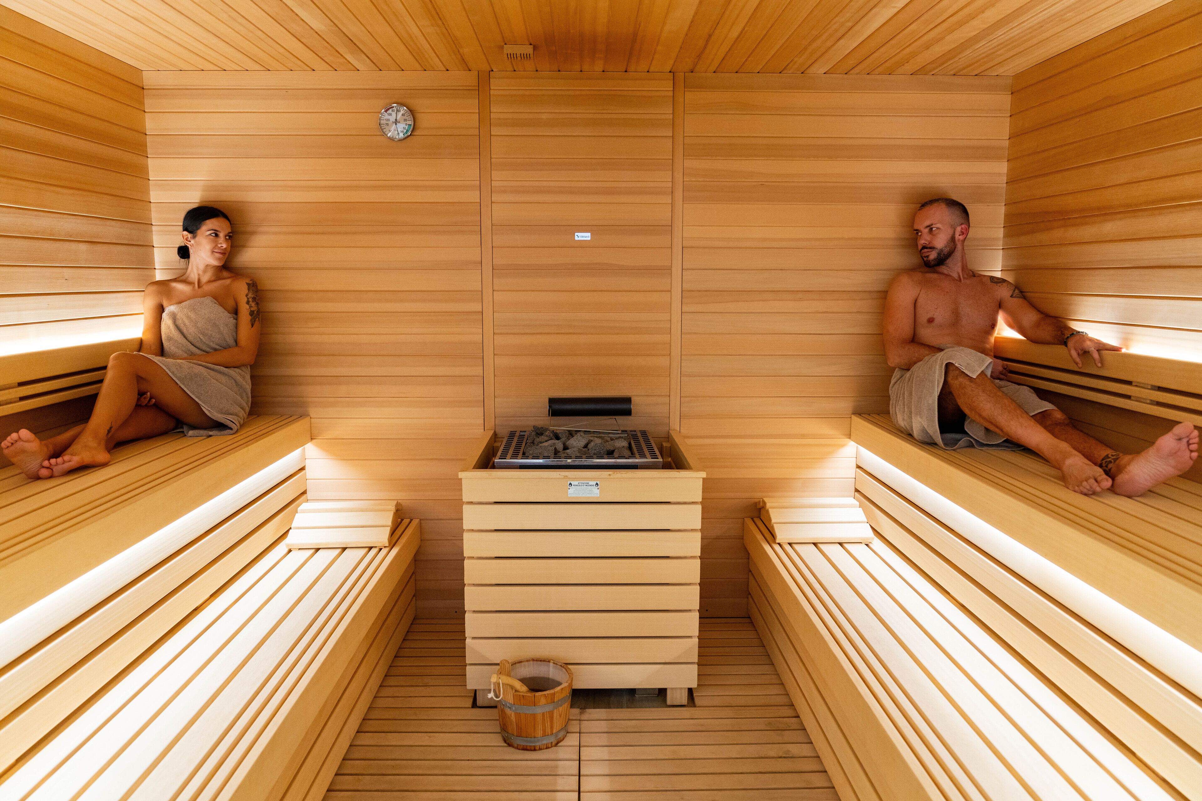 A sauna with wooden benches and a central heater.
