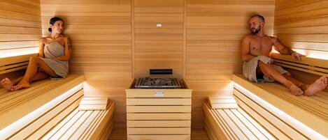 Una sauna con bancos de madera y un calentador central.