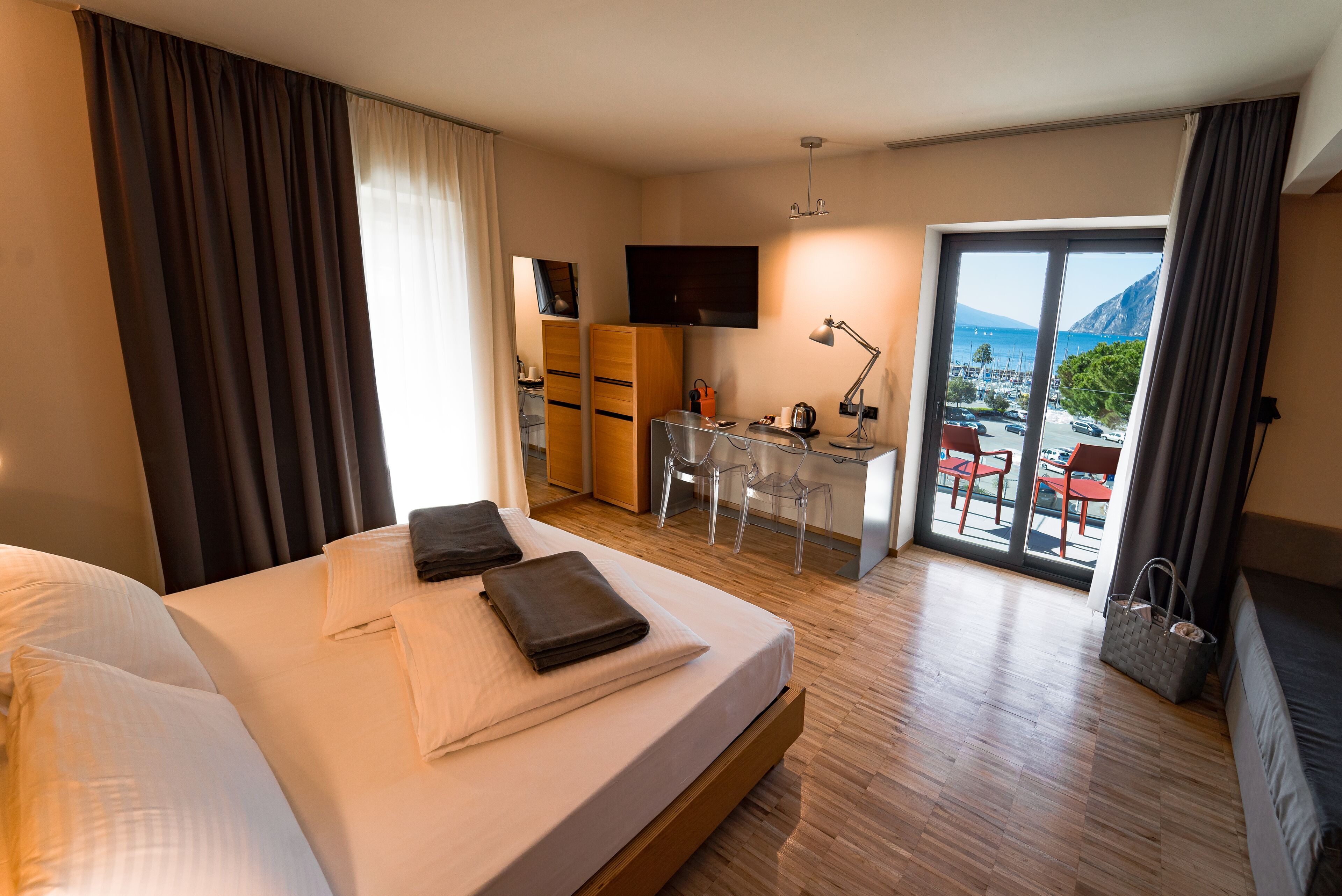 Habitación de hotel con cama, escritorio, televisor y vista al mar.