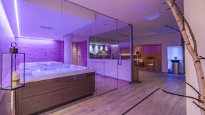 Et moderne spa-rum med et glasomkranset spabad, trægulv og et minimalistisk design.