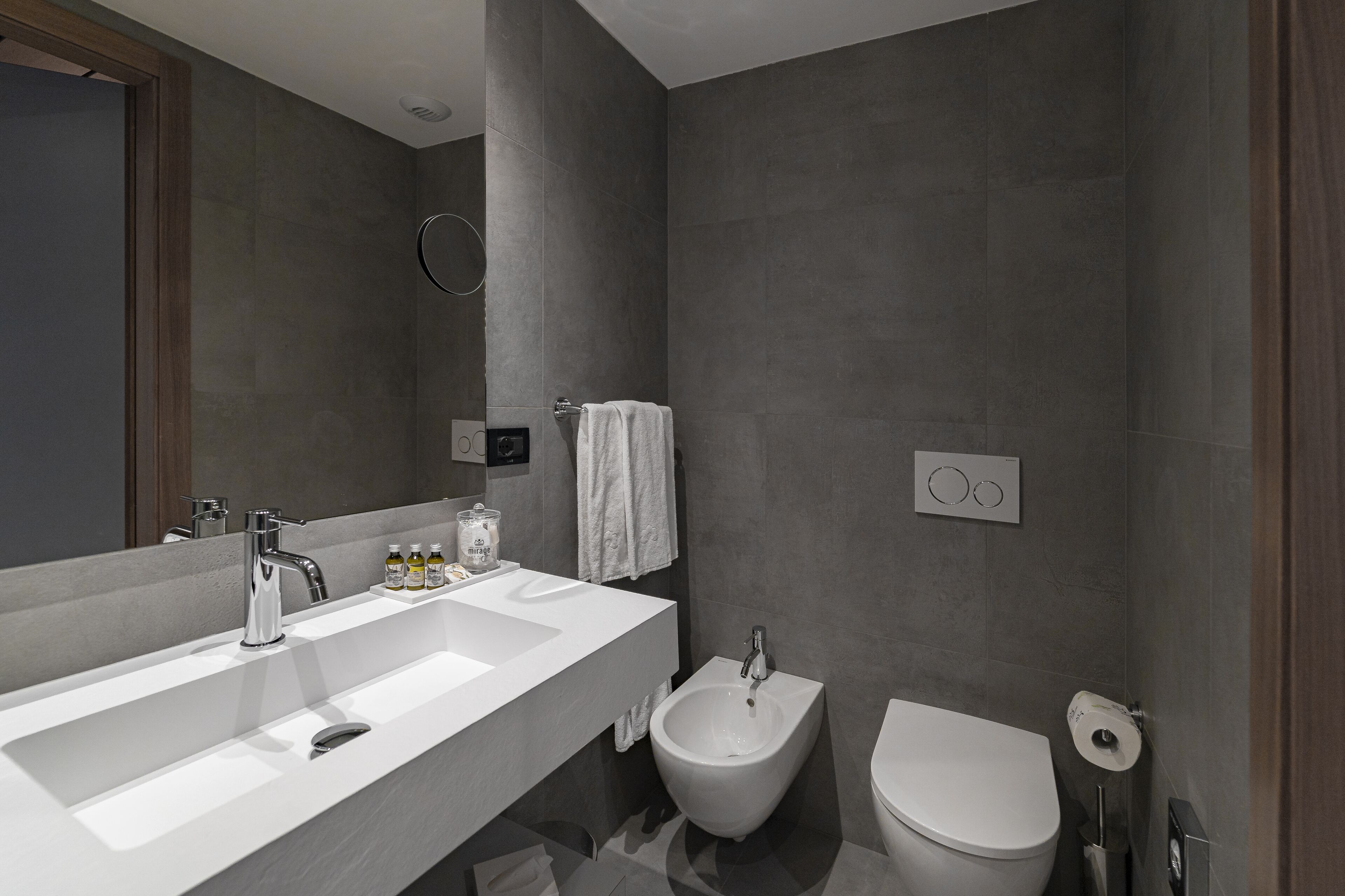 Un baño moderno con un espejo grande, dos lavamanos, un bidé y un inodoro.