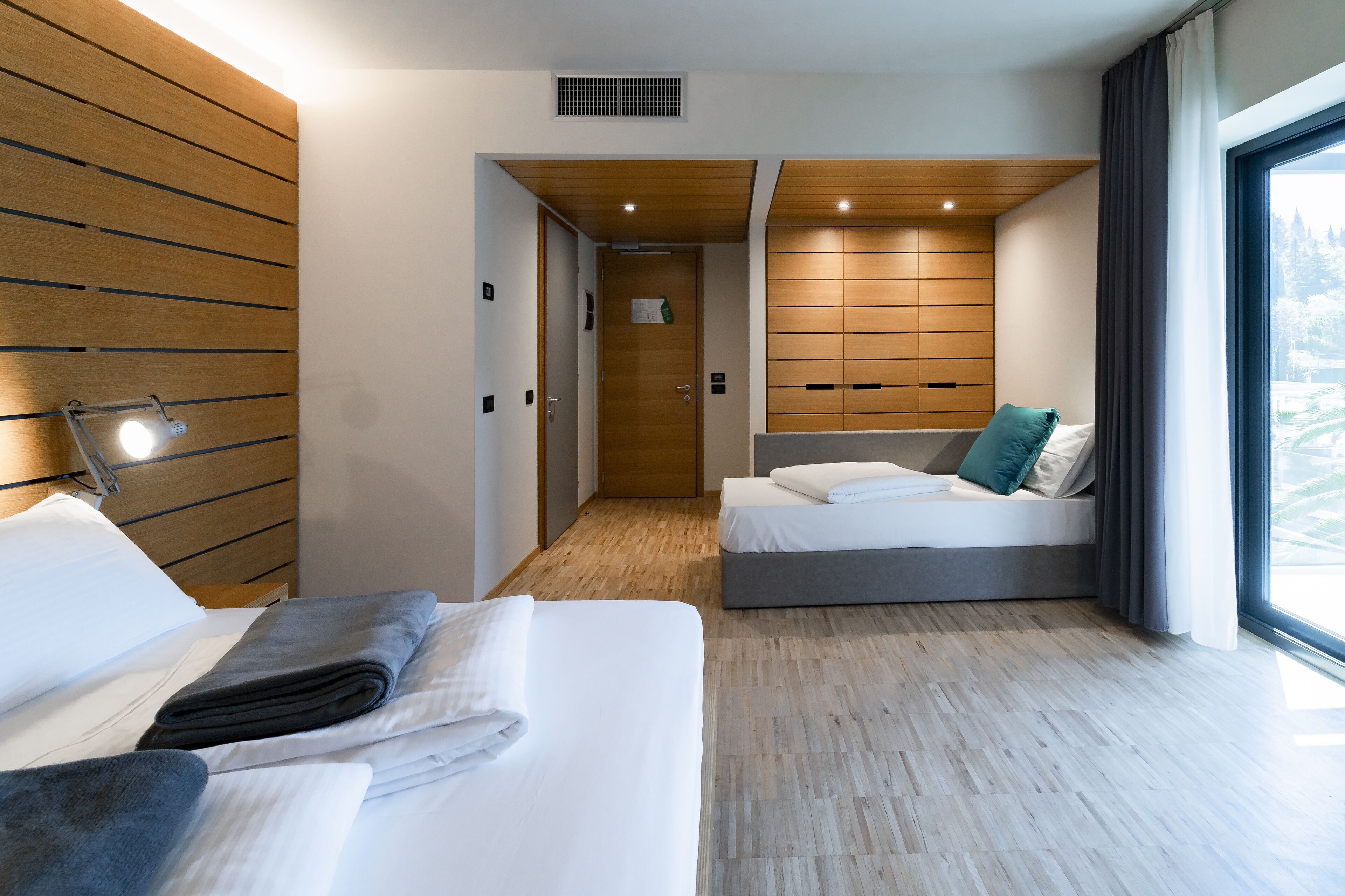 Una camera d'albergo moderna con un letto grande, un letto più piccolo e un'area salotto.