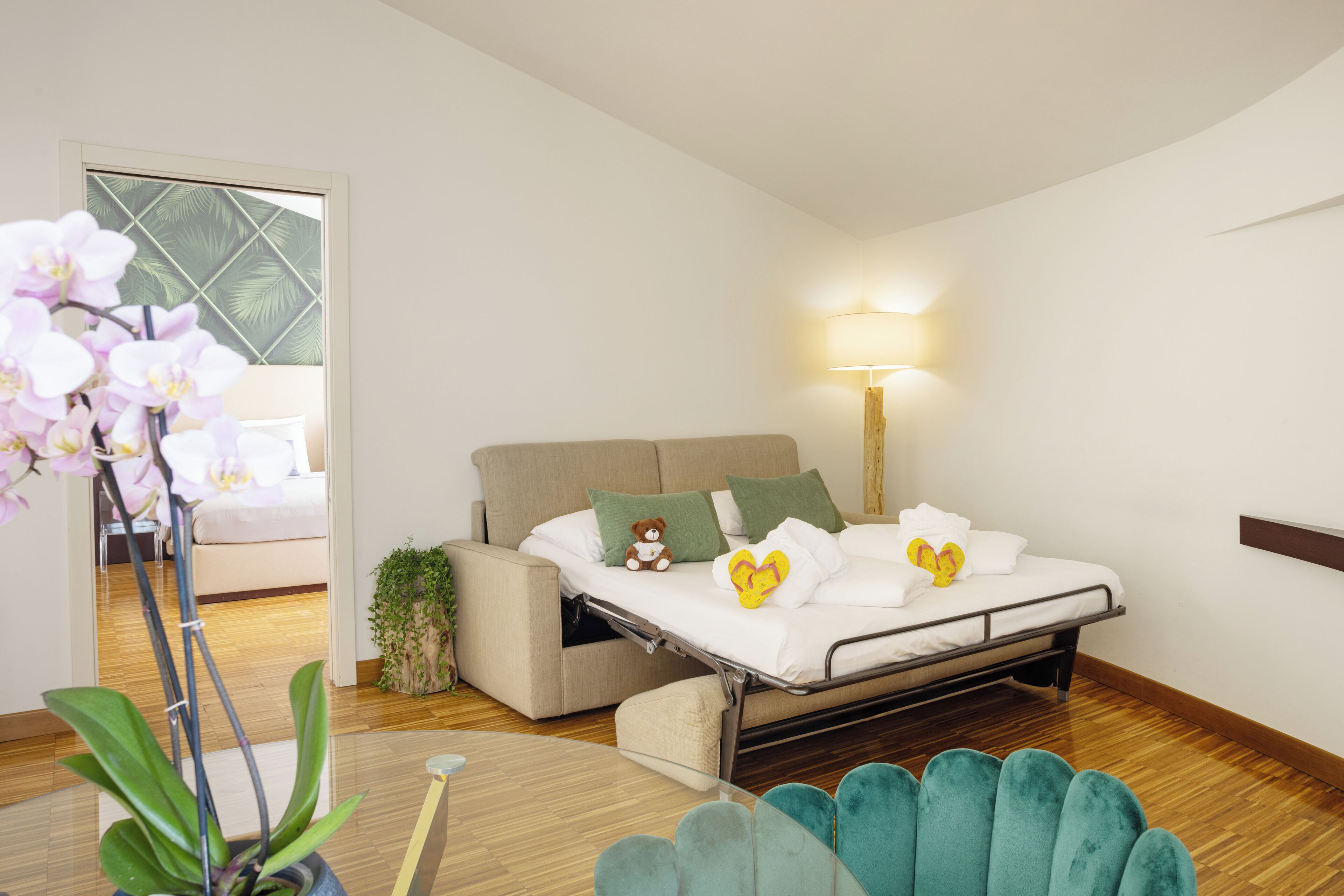 Camera da letto moderna con un letto, un comodino, una lampada e un'orchidea in vaso.