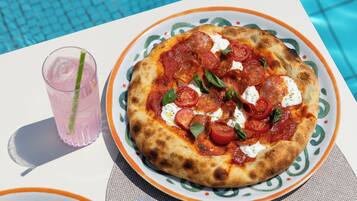 Due pizze su piatti, con una piscina sullo sfondo.