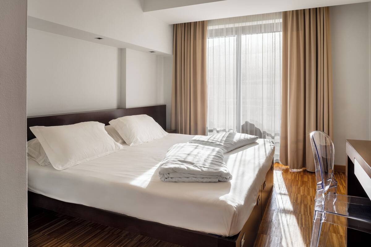 A hotel room with a large bed, a desk, and a chair.