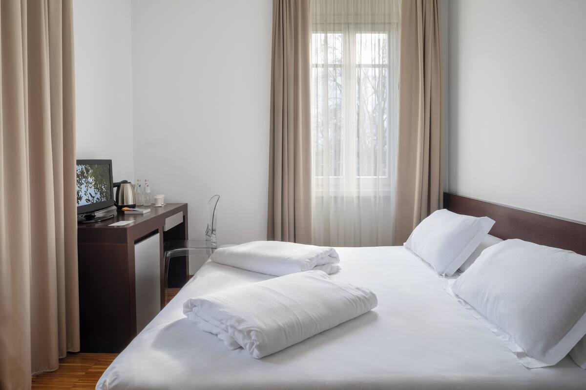 A hotel room with a bed, a desk, and a chair.