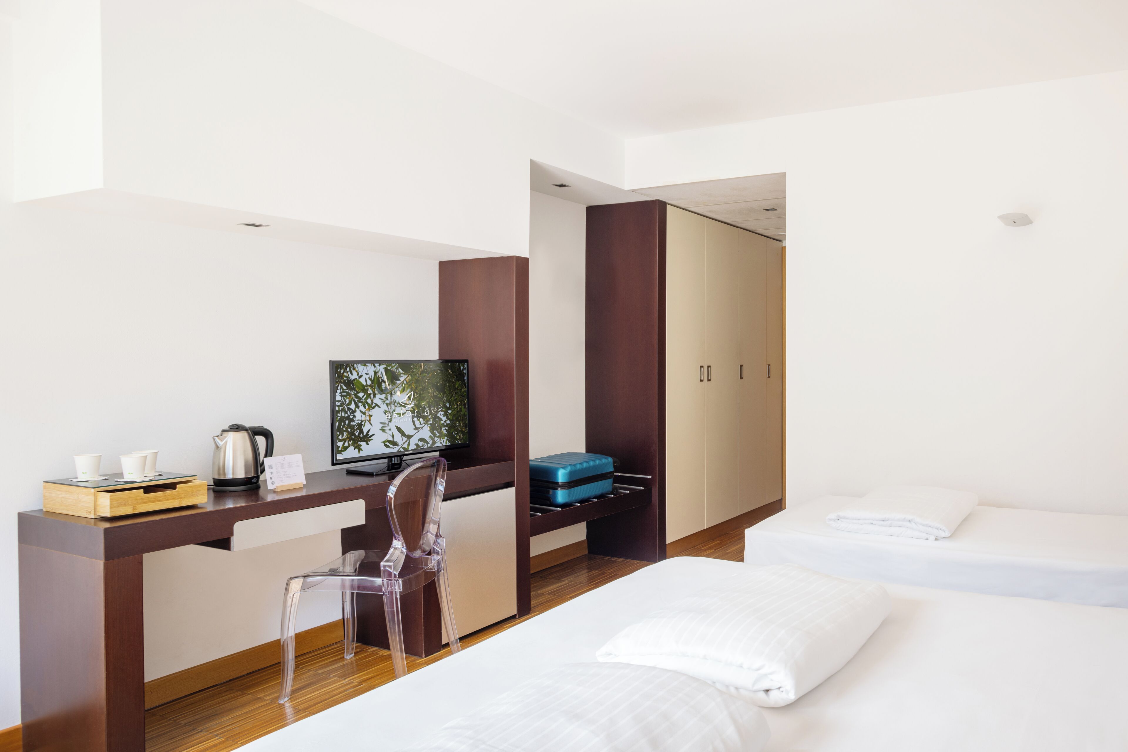 Une chambre d’hôtel équipée d’un bureau, d’une chaise, d’une télévision, d’un lit et d’une armoire.