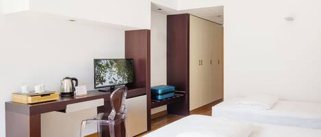 Une chambre d’hôtel équipée d’un bureau, d’une chaise, d’une télévision, d’un lit et d’une armoire.