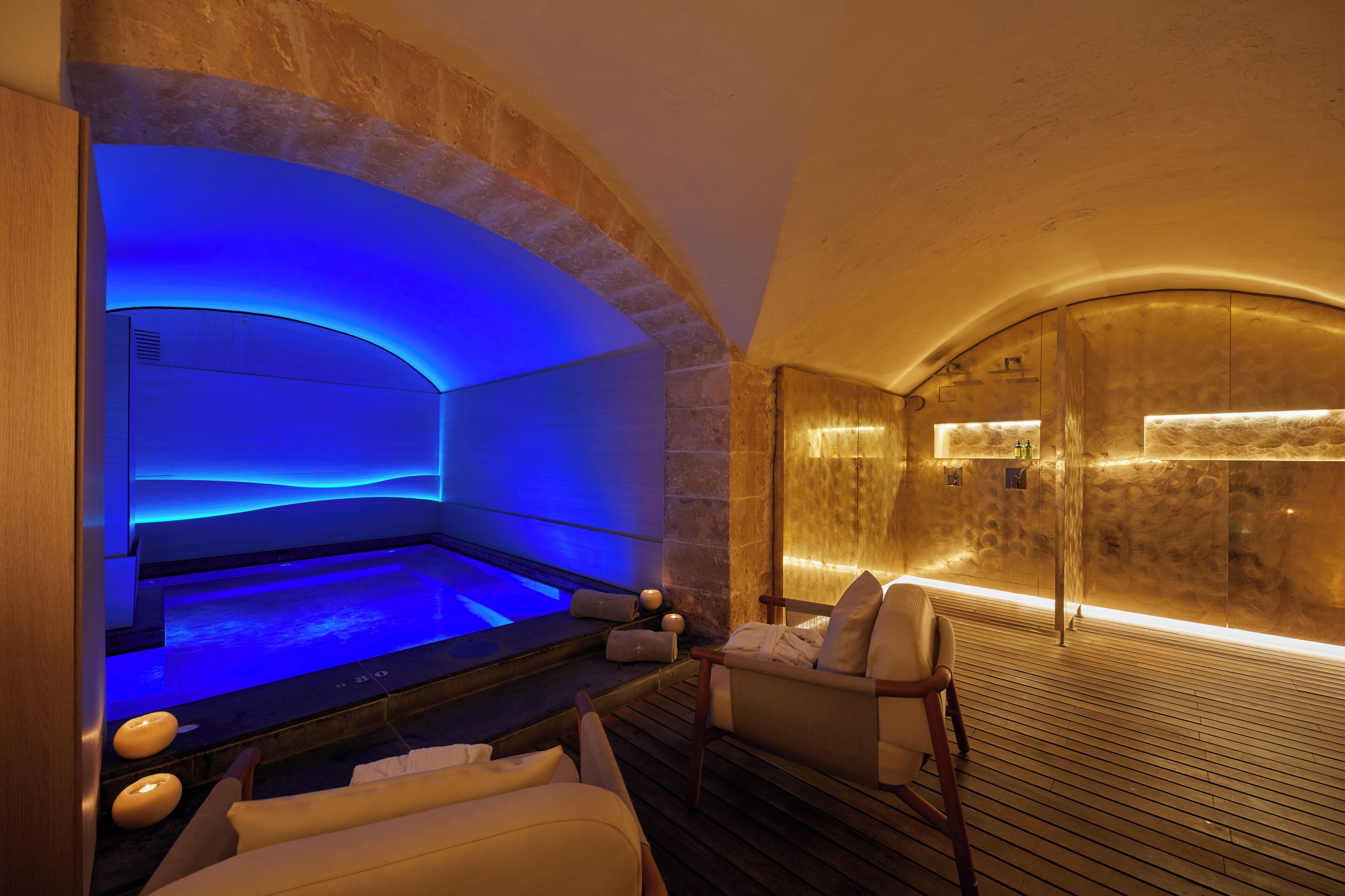 Un área de spa con piscina climatizada, asientos y piso de madera.