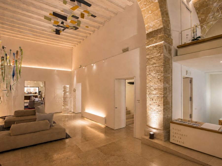 Un vestíbulo de hotel con diseño moderno, que incluye un sofá, una recepción y una escalera.