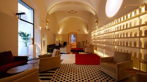 A lobby with a checkered floor, sofas, a red carpet, and a wall of vases. - Convent de la Missio Boutique Hotel GL, Adults Only – Preferred Hotels & Resorts (Palma de Mallorca)