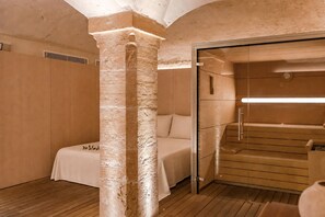 Ein Zimmer mit einem Bett, Holzboden, einer Glastür zu einem Duschbereich und einer Wandkonsole mit Struktur.