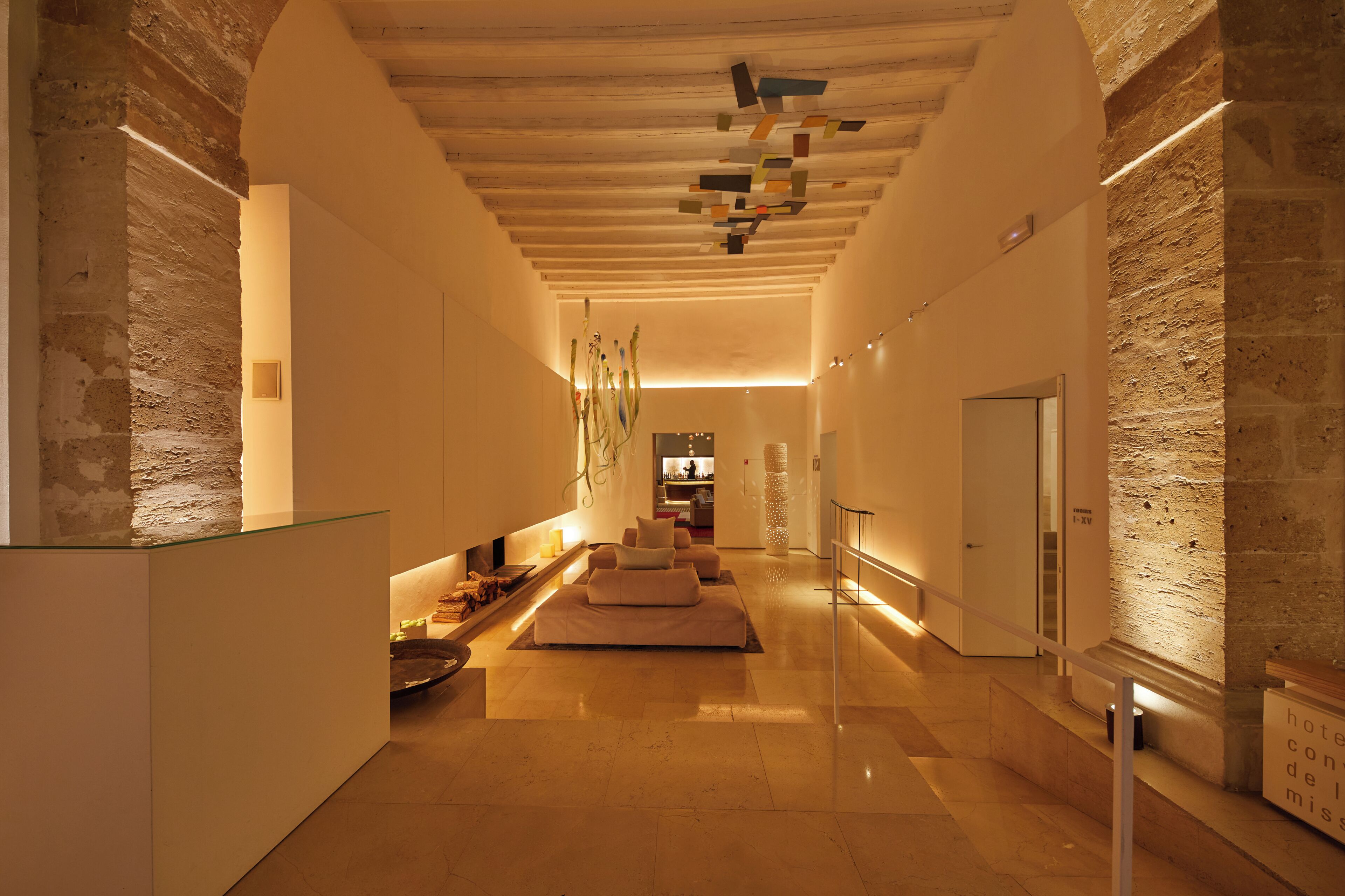 Een moderne hotellobby met een centraal zithoek, een receptiebalie en een trap naar de verdiepingen.