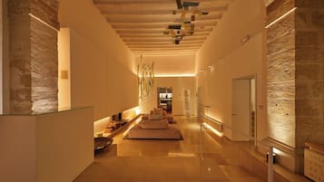 Een moderne hotellobby met een centraal zithoek, een receptiebalie en een trap naar de verdiepingen.
