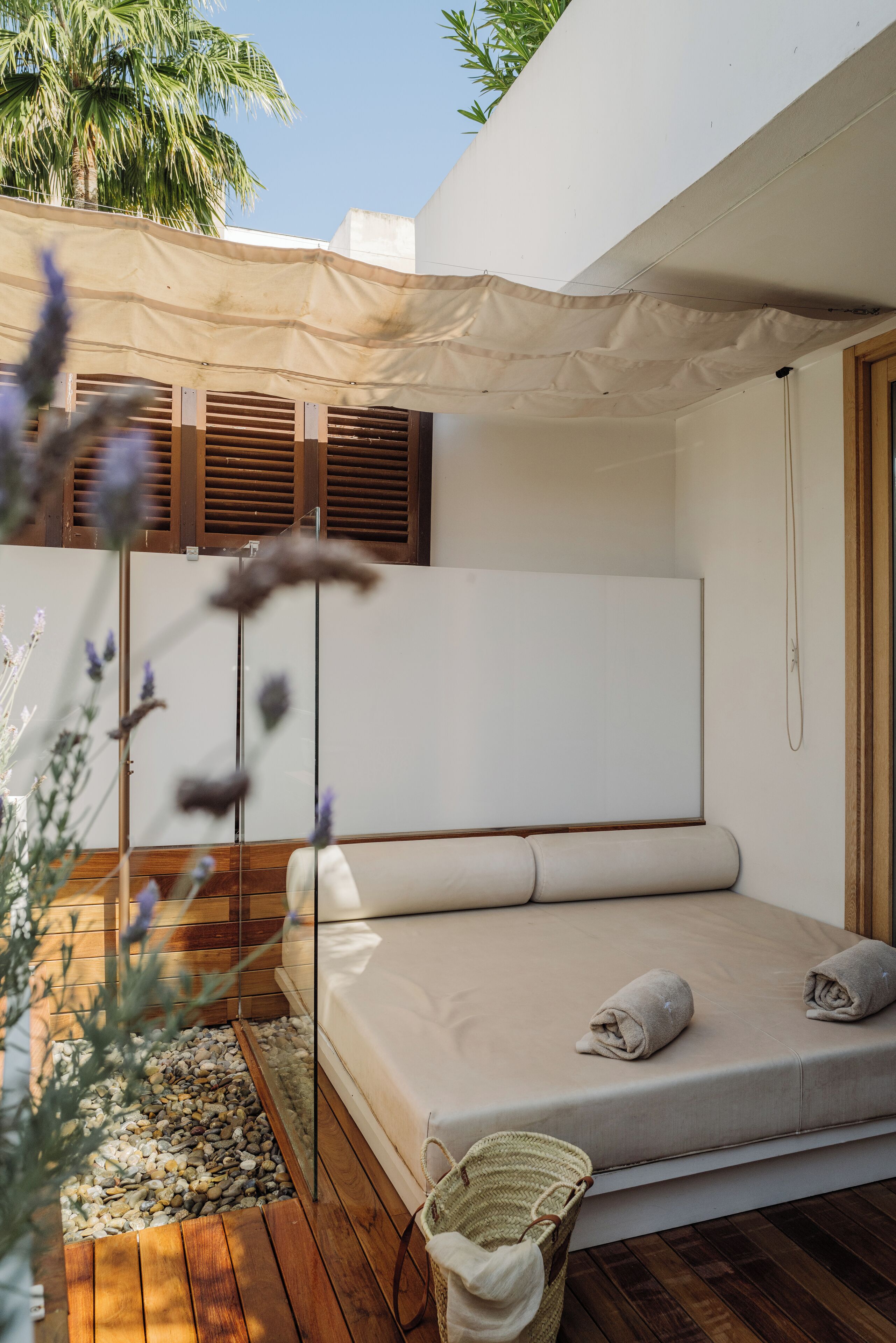 Een moderne slaapkamer buiten, met een matras, een geweven mand en een houten vloer.