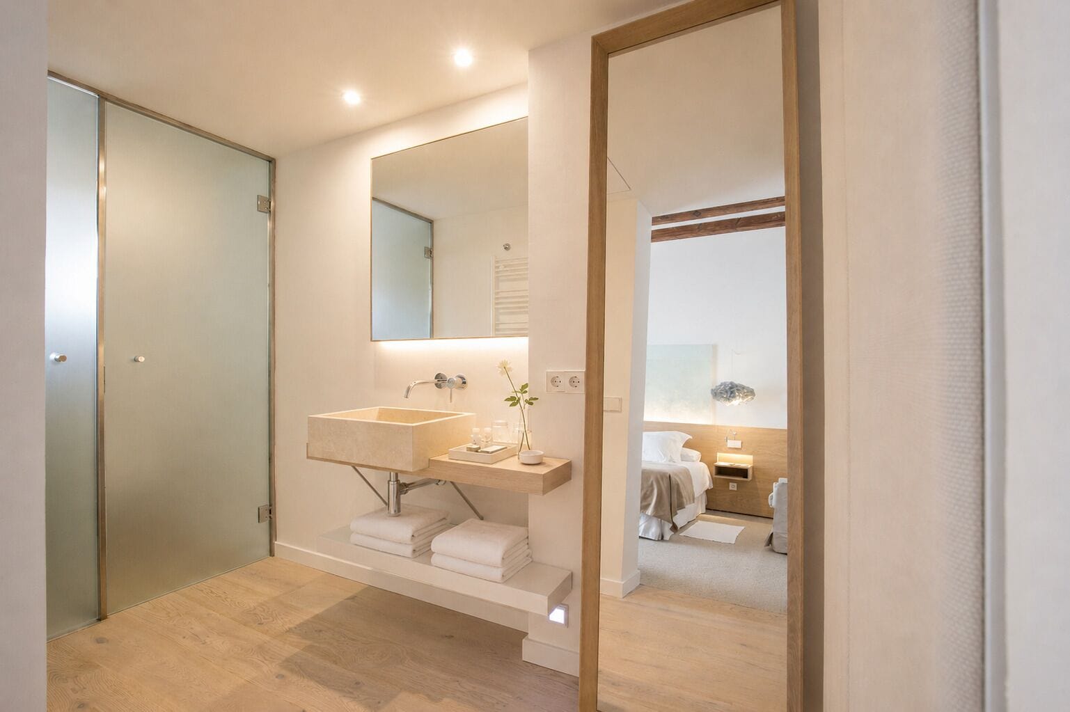 A modern bathroom with a double sink, a large mirror, and a wooden floor.