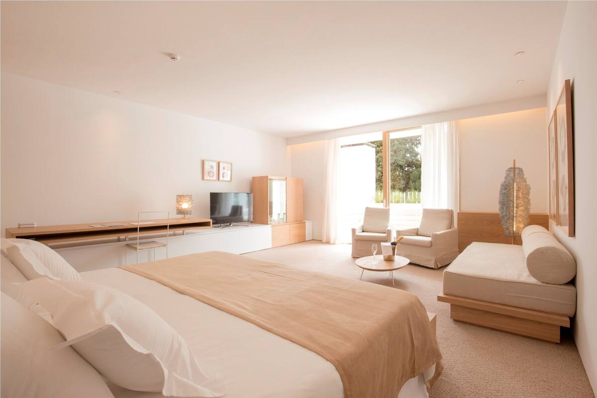 Une chambre d’hôtel moderne équipée d’un grand lit, d’un canapé, d’une télévision et d’une table à manger.