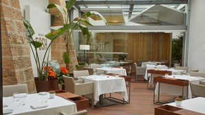 A restaurant with multiple tables and chairs, a brick wall, and a large window. - Convent de la Missio Boutique Hotel GL, Adults Only – Preferred Hotels & Resorts (Palma de Mallorca)