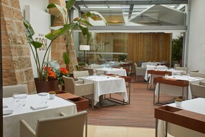 Un restaurant avec plusieurs tables et chaises, un mur en briques et une grande fenêtre.