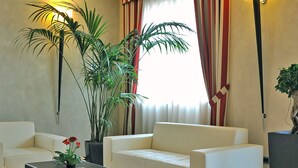 Un moderno vestíbulo de hotel con un sofá blanco, una mesita de centro y dos grandes macetas.