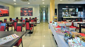Un restaurante con mesas y sillas, un bufé de comida y un pilar grande.