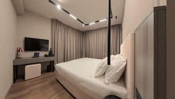 A modern hotel room with a large bed, a desk with a flat-screen TV, and a wardrobe.