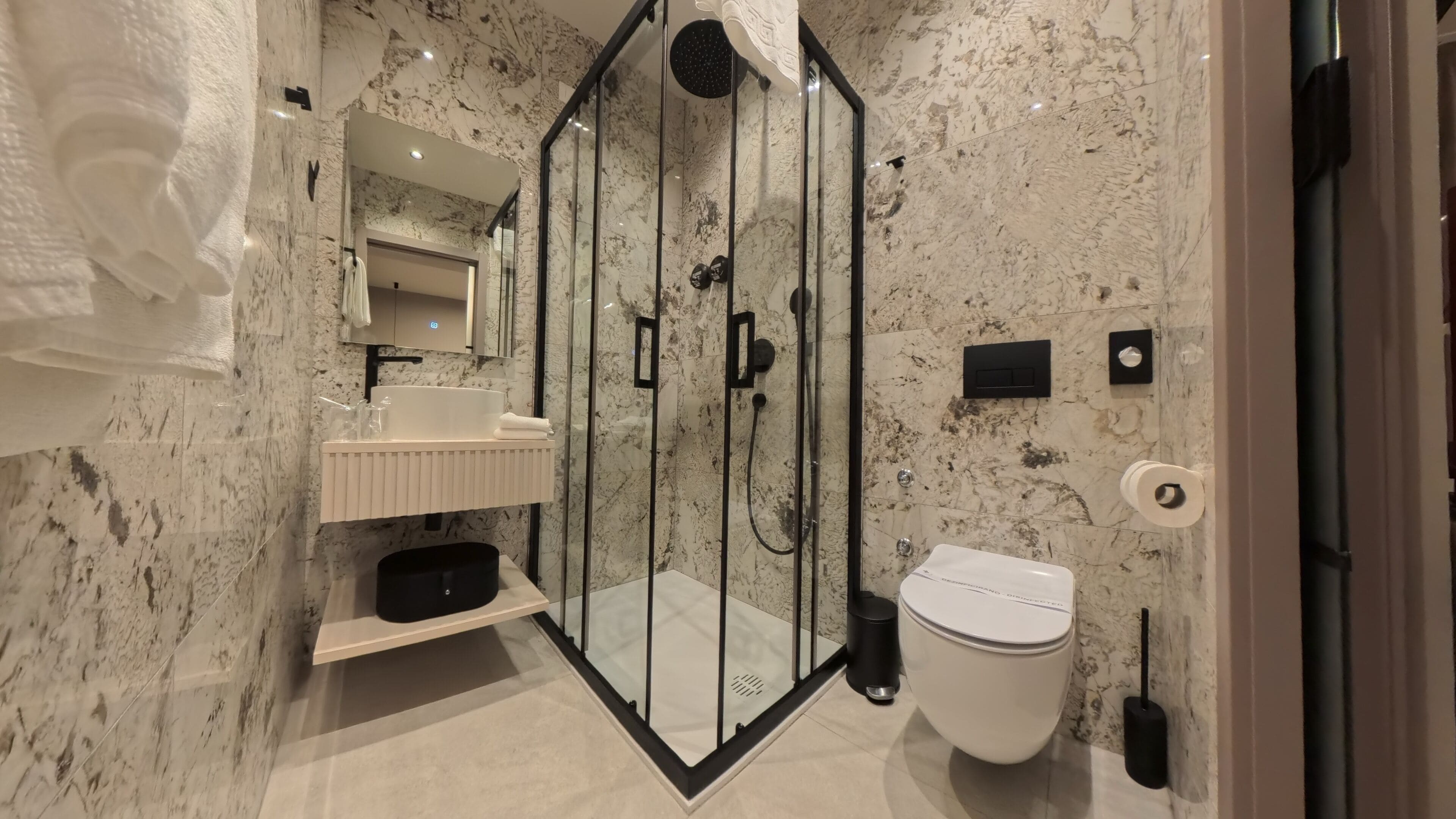 Un baño moderno con ducha envuelta en vidrio, un lavabo blanco y un inodoro.